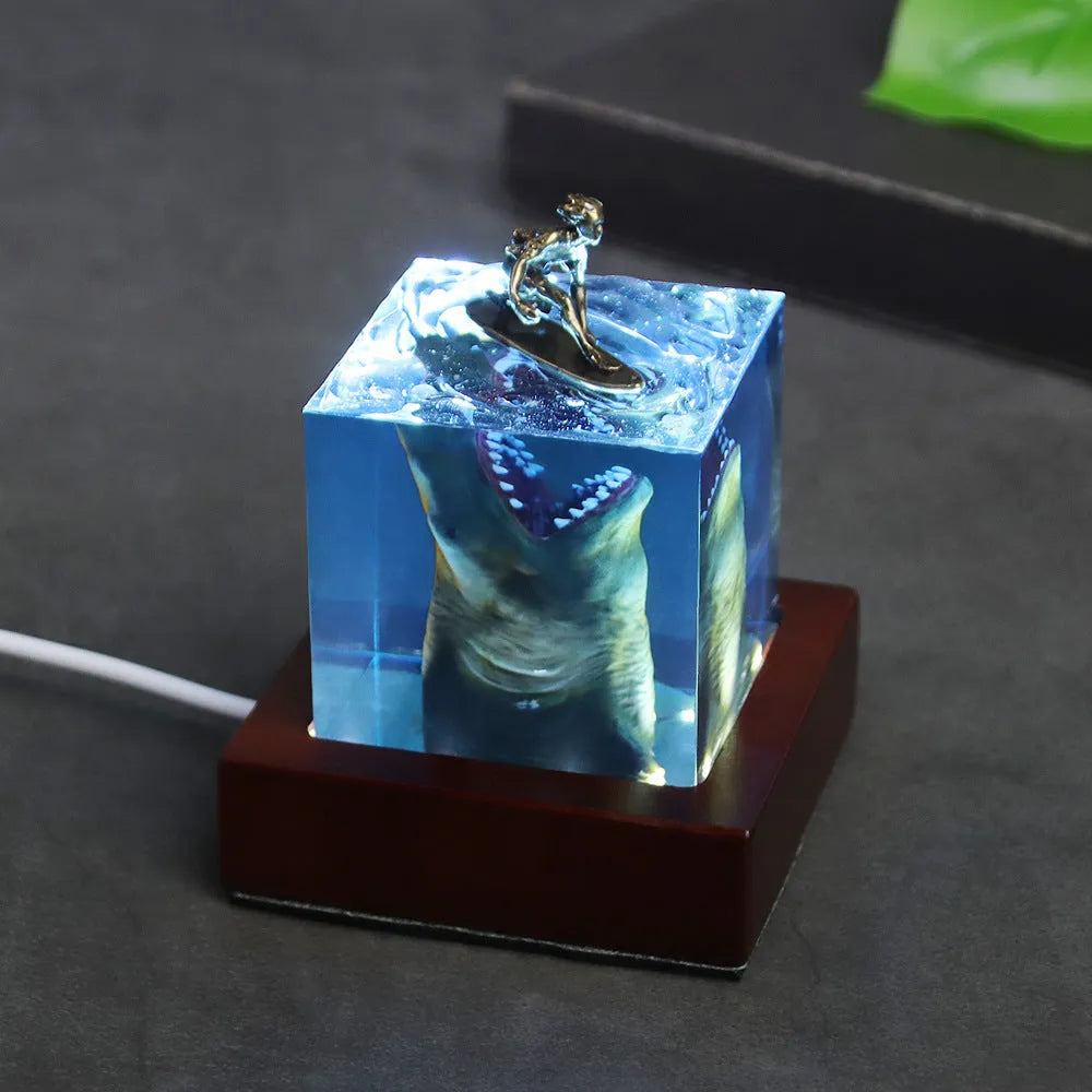 Clear epoxy resin ornament with shark surfer scene inside, next to 5cm and 8cm size options.