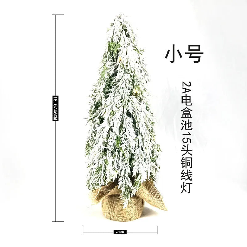 Small 24-inch artificial Christmas tree with white PE snow spray finish, green branches, built-in lights, and a red ornament