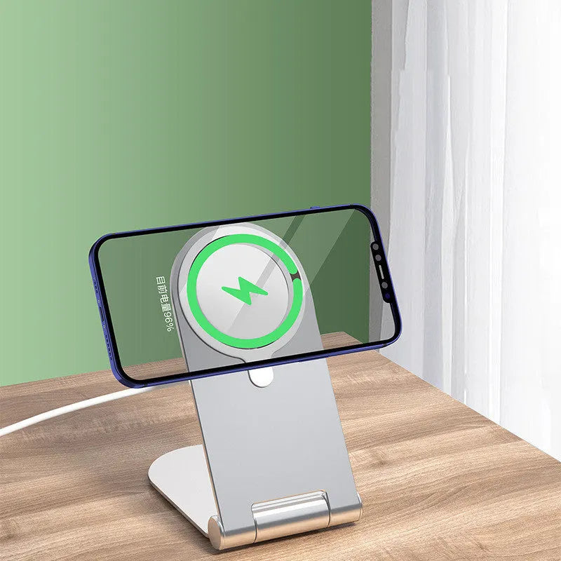 Silver vertical adjustable magnetic phone bracket for iPhone 12 models on a desk.
