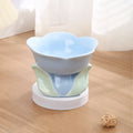 Blue floral patterned ceramic raised pet bowl for cats and dogs on a wooden floor.