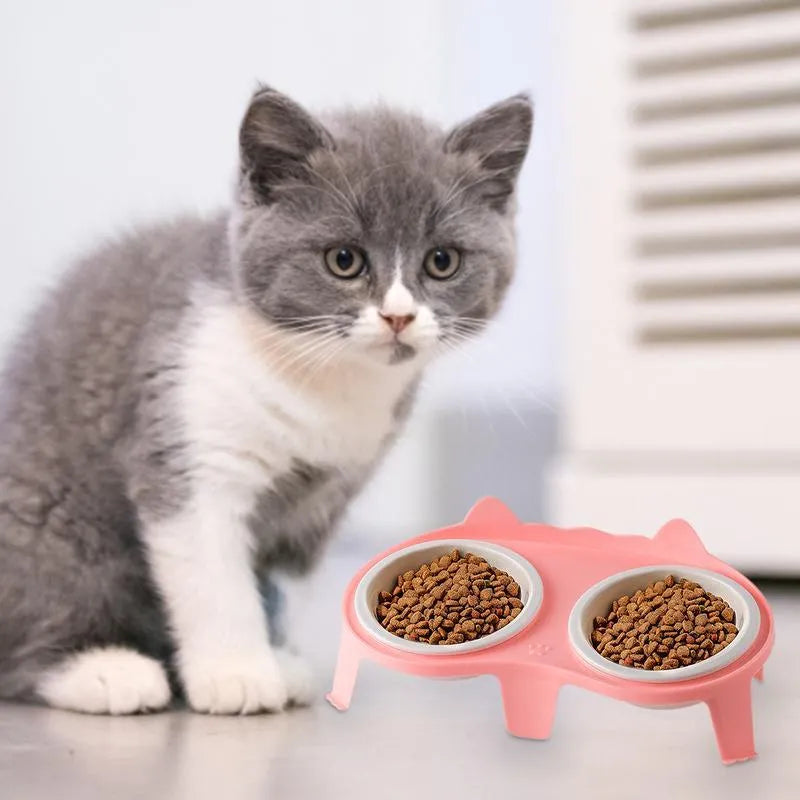 Blue ceramic cat bowl set on white elevated stand with hook, showing tilted food and water dishes.