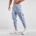 Man wearing loose fit apricot coloured cotton sports trousers with ankle ties and multiple pockets.