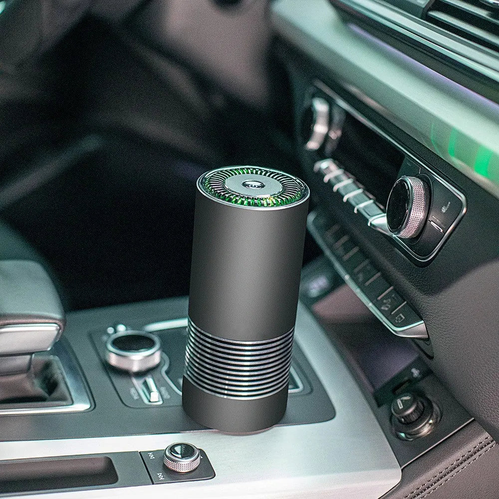 Compact black metallic car air purifier with USB cable on a car dashboard.