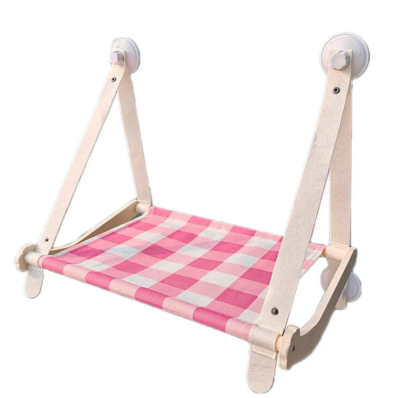 Pink wooden cat hammock bed with suction cups attached to a window