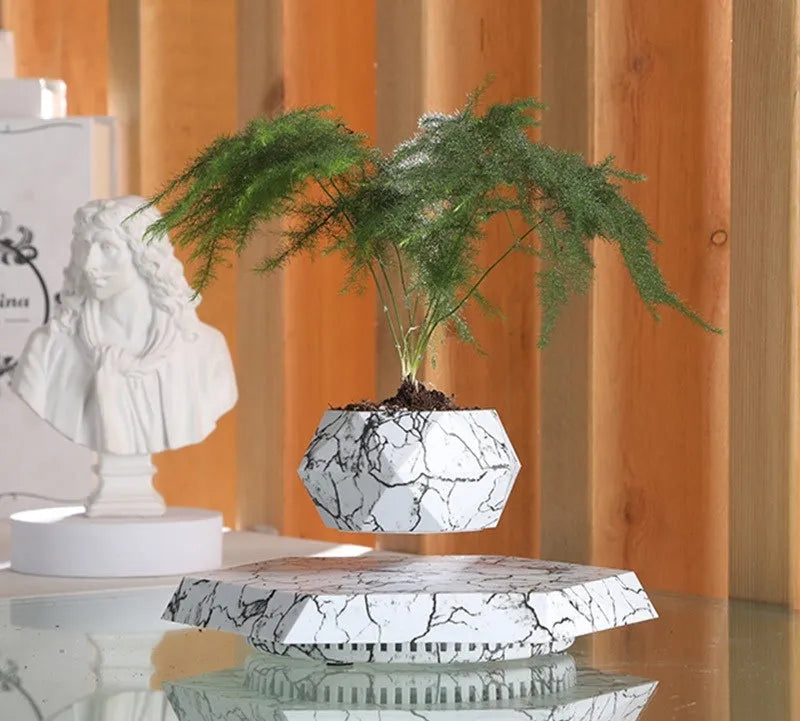Small marble-colour magnetic levitation plant pot floating and rotating above its floor-standing base.