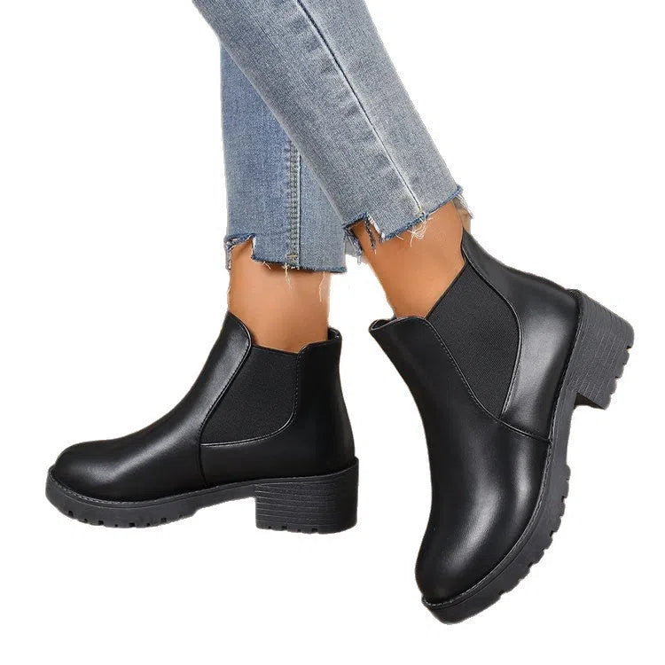 Black Chelsea ankle boots for women with flat chunky heel, round toe, and cloth upper on a light background
