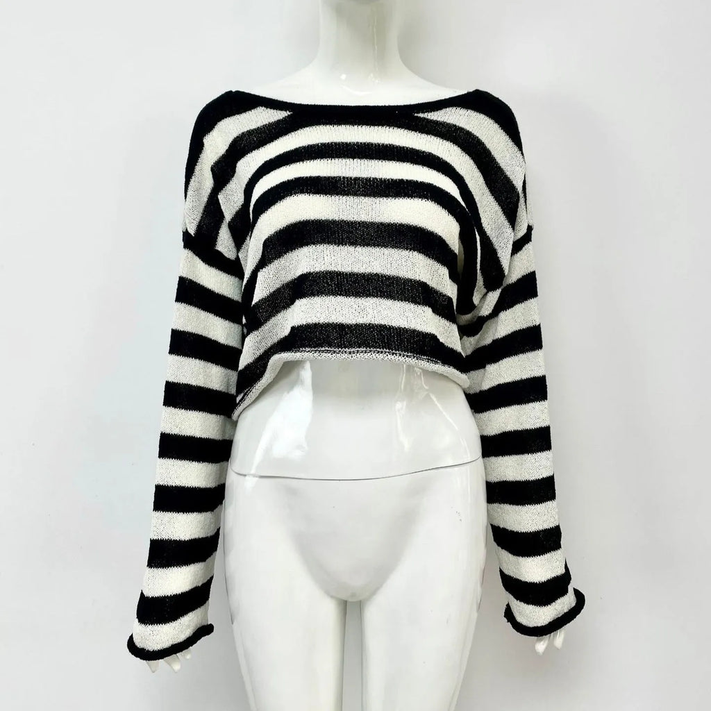 A woman wearing a black and white striped, cropped, long-sleeved sweater, showing the front and back reversible design.