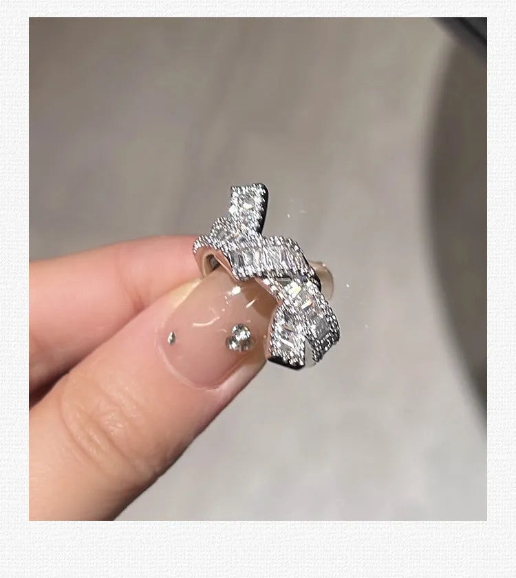 Silver cross open ring with bow shape in copper with electroplated finish on neutral background