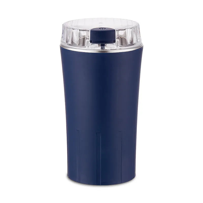 Blue mini flour mill and grain crusher with stainless steel grinding chamber on a countertop.