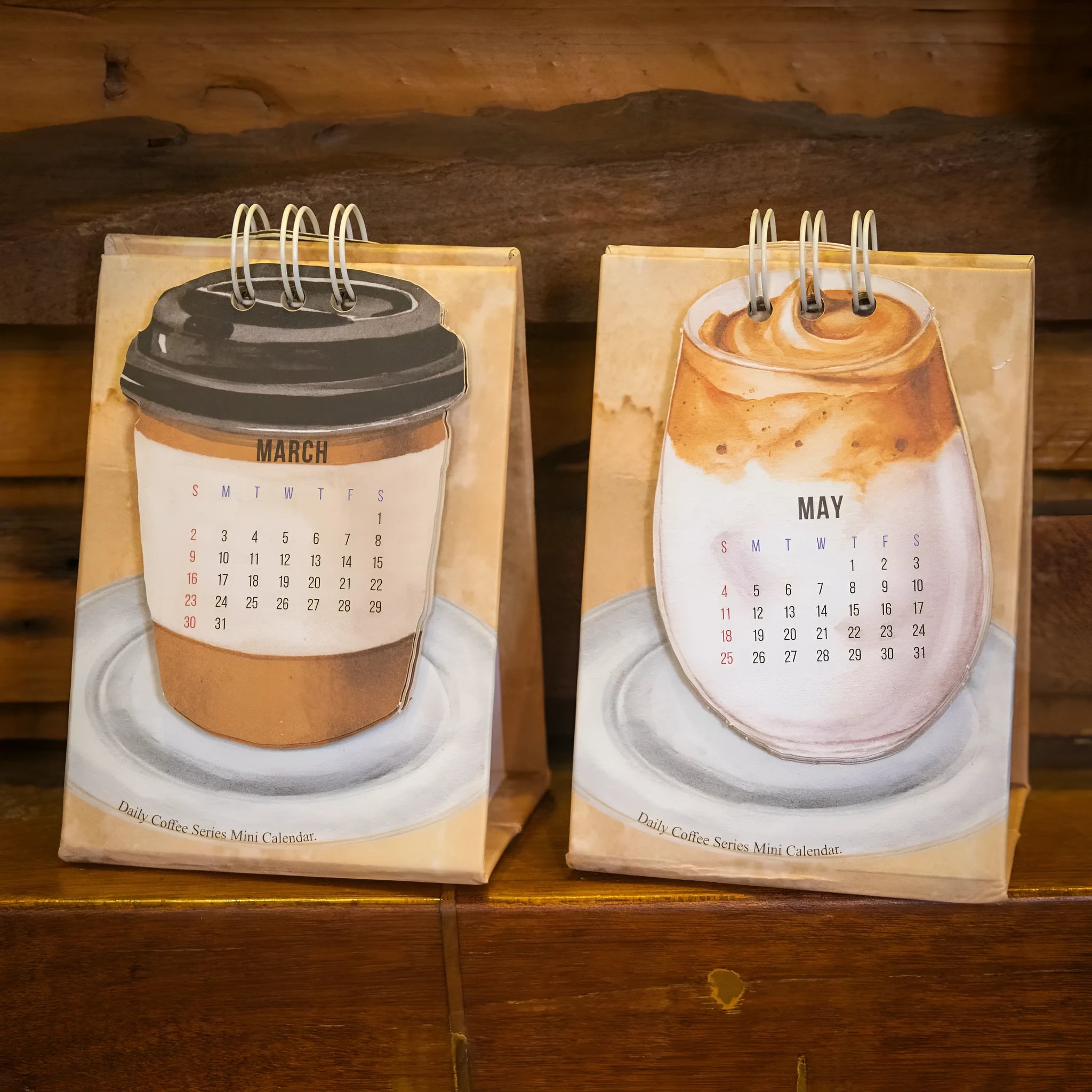 Set of four different 2025 mini paper desk calendars with simple modern designs on a desk.