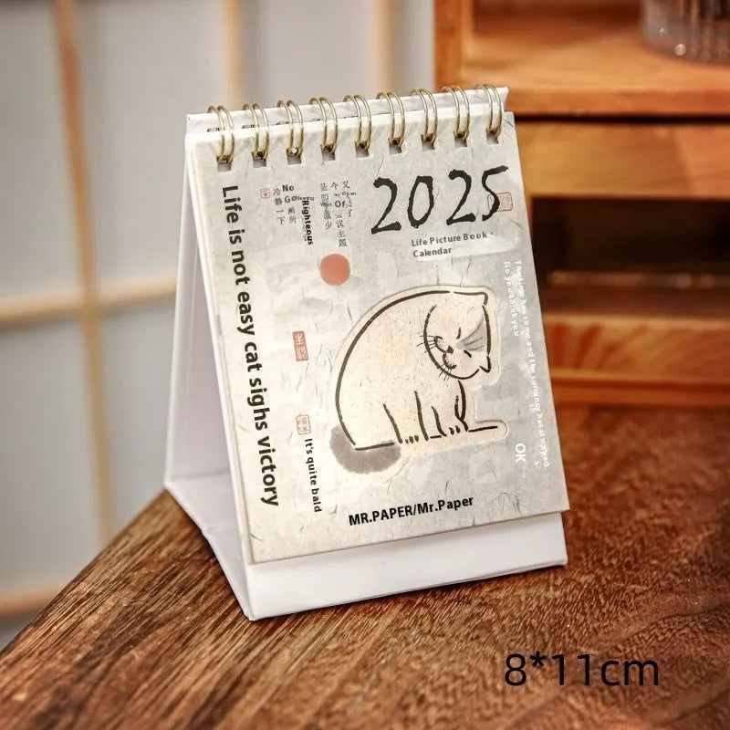 Set of four different 2025 mini paper desk calendars with simple modern designs on a desk.