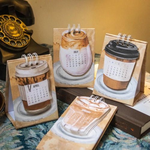 Set of four different 2025 mini paper desk calendars with simple modern designs on a desk.