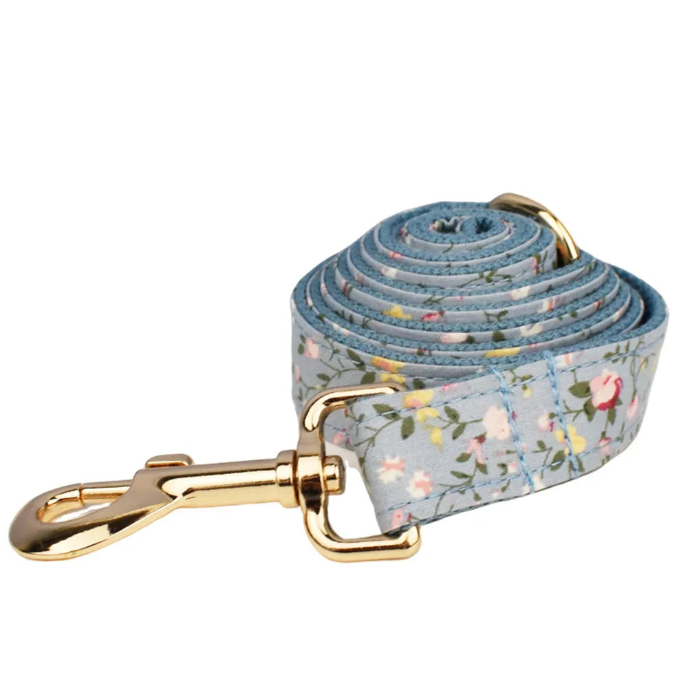 Blue floral pattern dog collar set with matching leash, vest, and accessories on white background