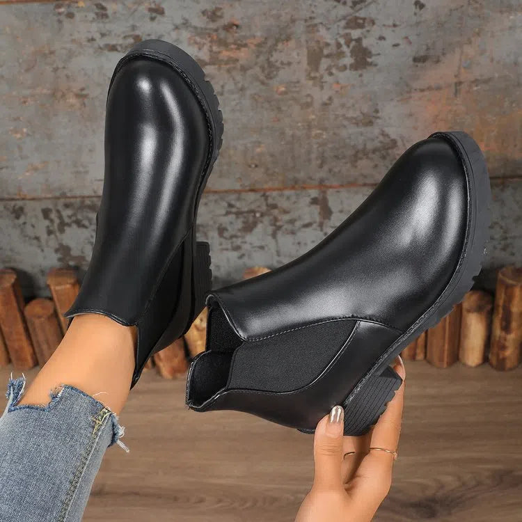 Black Chelsea ankle boots for women with flat chunky heel, round toe, and cloth upper on a light background