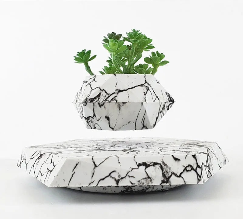 Small marble-colour magnetic levitation plant pot floating and rotating above its floor-standing base.