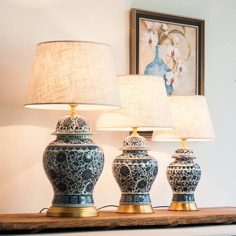 Handmade blue and white porcelain Chinese table lamp with a cloth shade on a wooden surface.