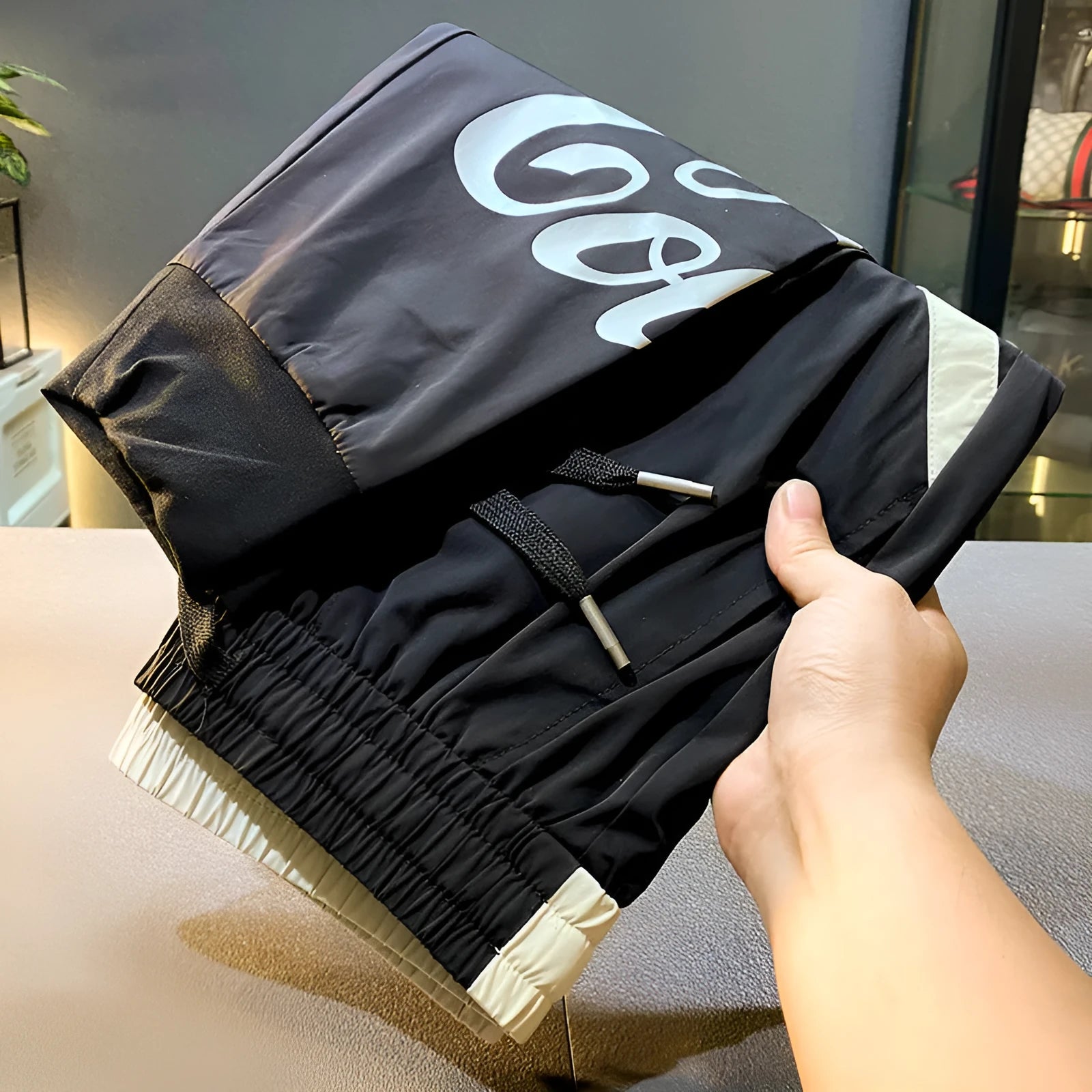 Black men's ultra-thin cotton ankle banded cropped trousers laid flat showing casual design
