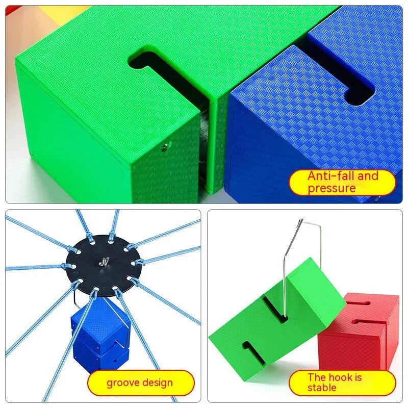 Outdoor team building equipment set with coloured plastic blocks, pull ropes, and a metal hook frame on grass.