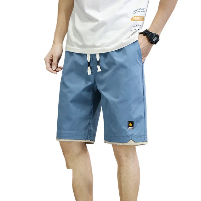 Man wearing loose fit casual polyester shorts in a green colour, showcasing the fifth pants length and Korean style.