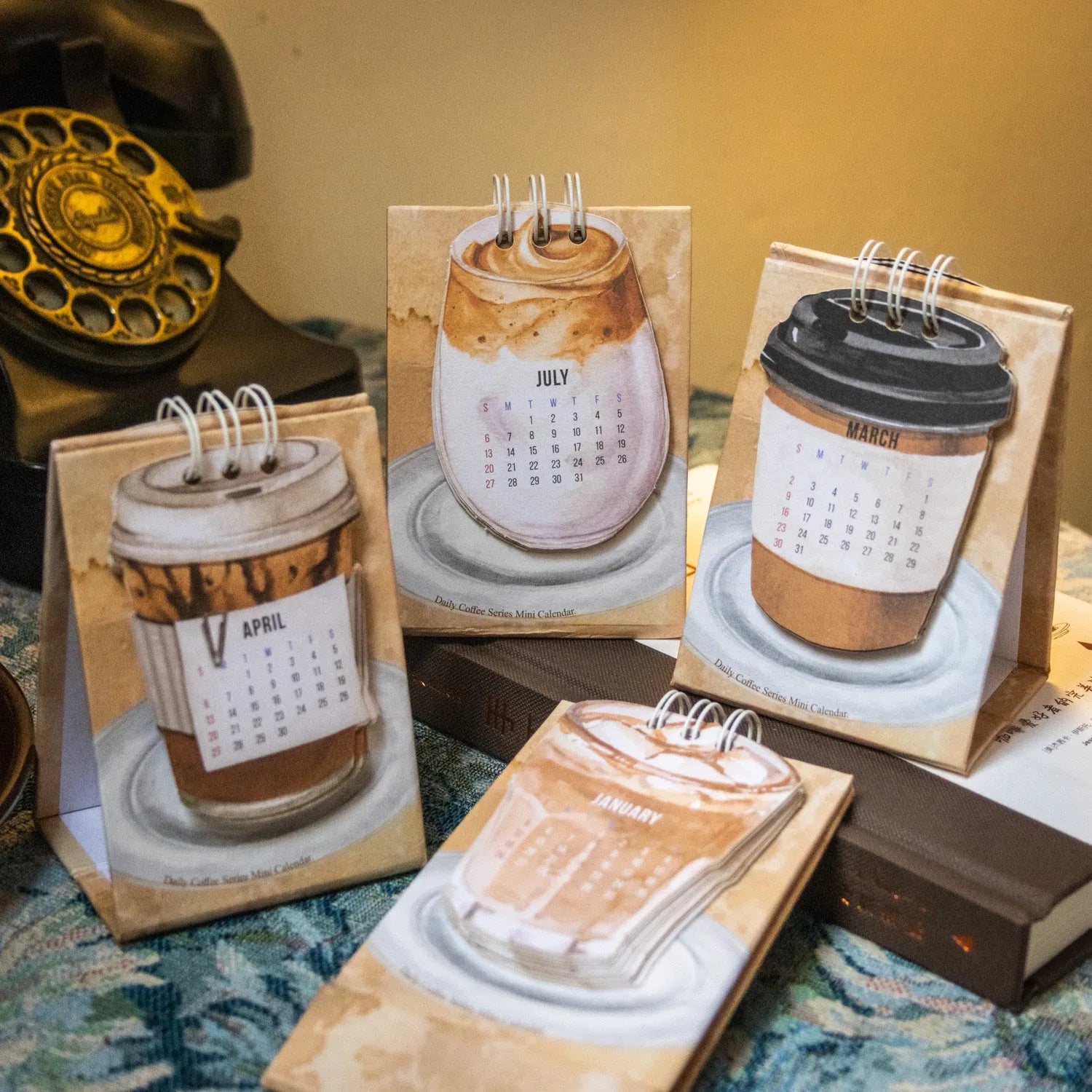 Set of four different 2025 mini paper desk calendars with simple modern designs on a desk.