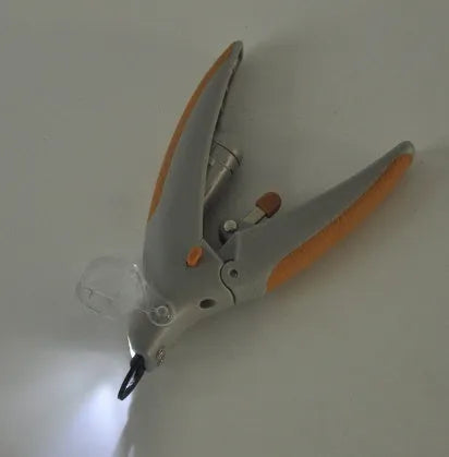 White battery-powered dog nail trimmer with built-in light and blood line guide on a blister card.