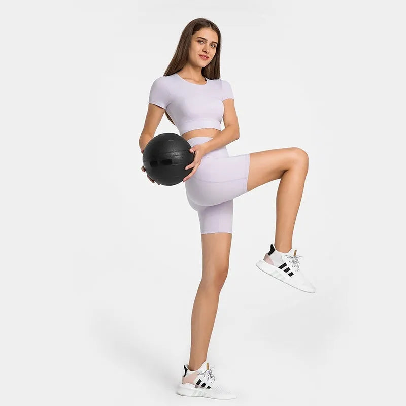 Women's tight-fit cotton blend sports shorts in light purple lotus colour, showing short fifth pants length.