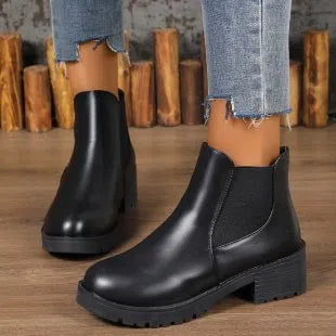 Black Chelsea ankle boots for women with flat chunky heel, round toe, and cloth upper on a light background