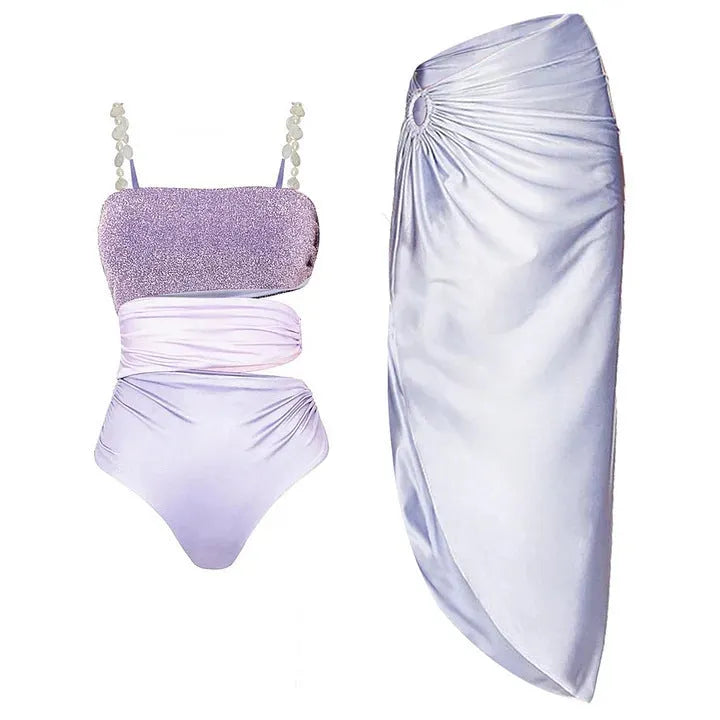 Purple one-piece swimsuit with a matching wrap skirt laid flat on a surface.