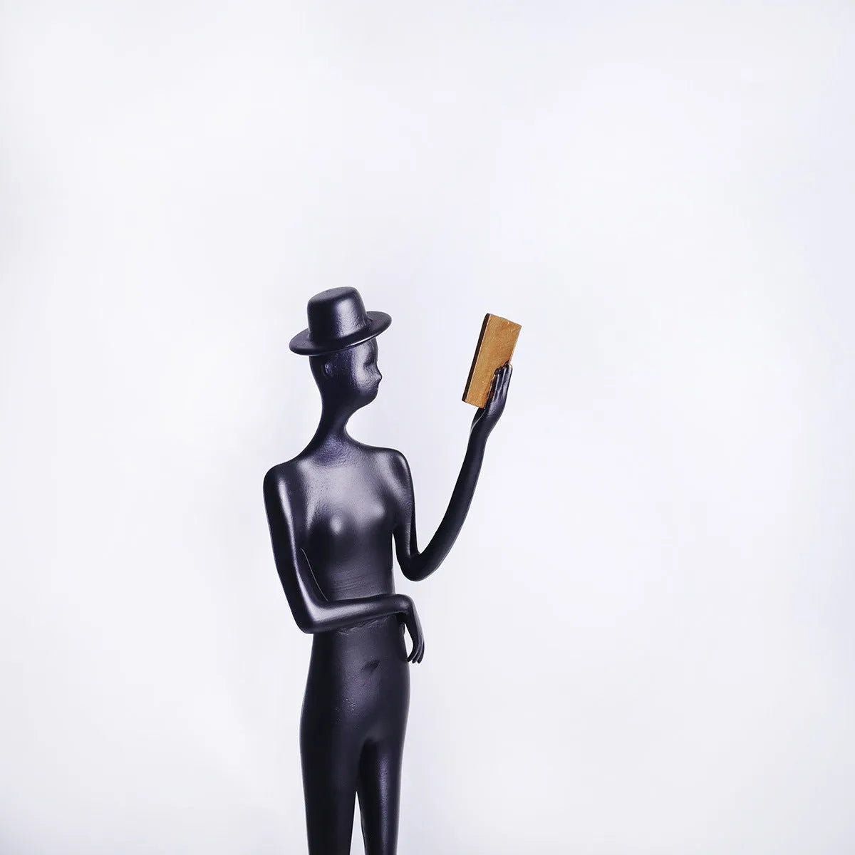 Black cast aluminium sculpture of a woman reading, measuring 51cm tall on a desktop.