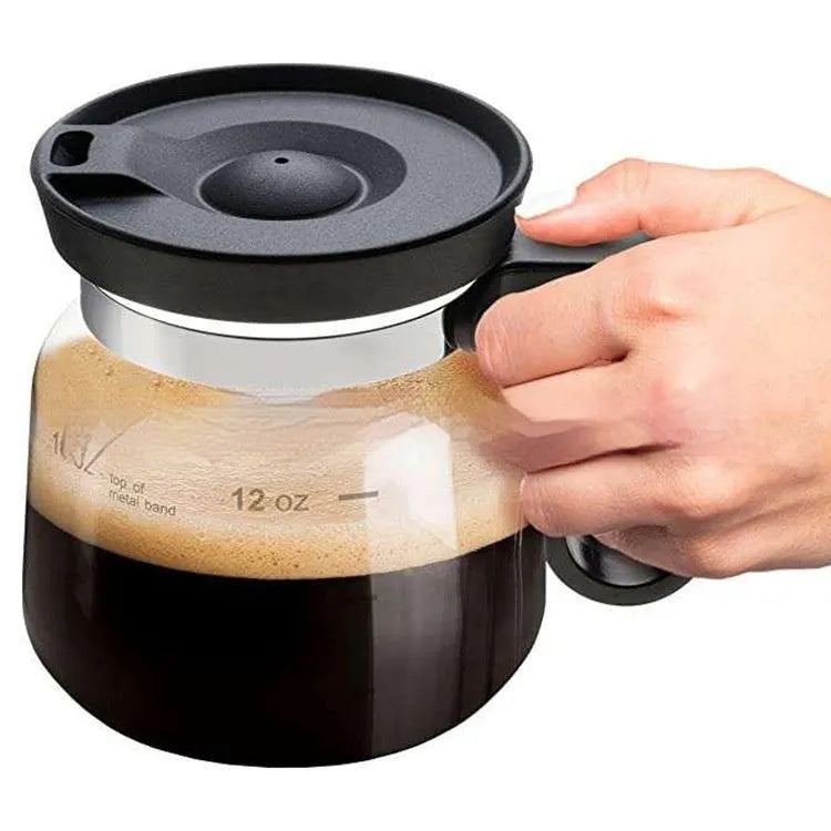 Transparent borosilicate glass coffee maker with a black silicone cover on a wooden table.