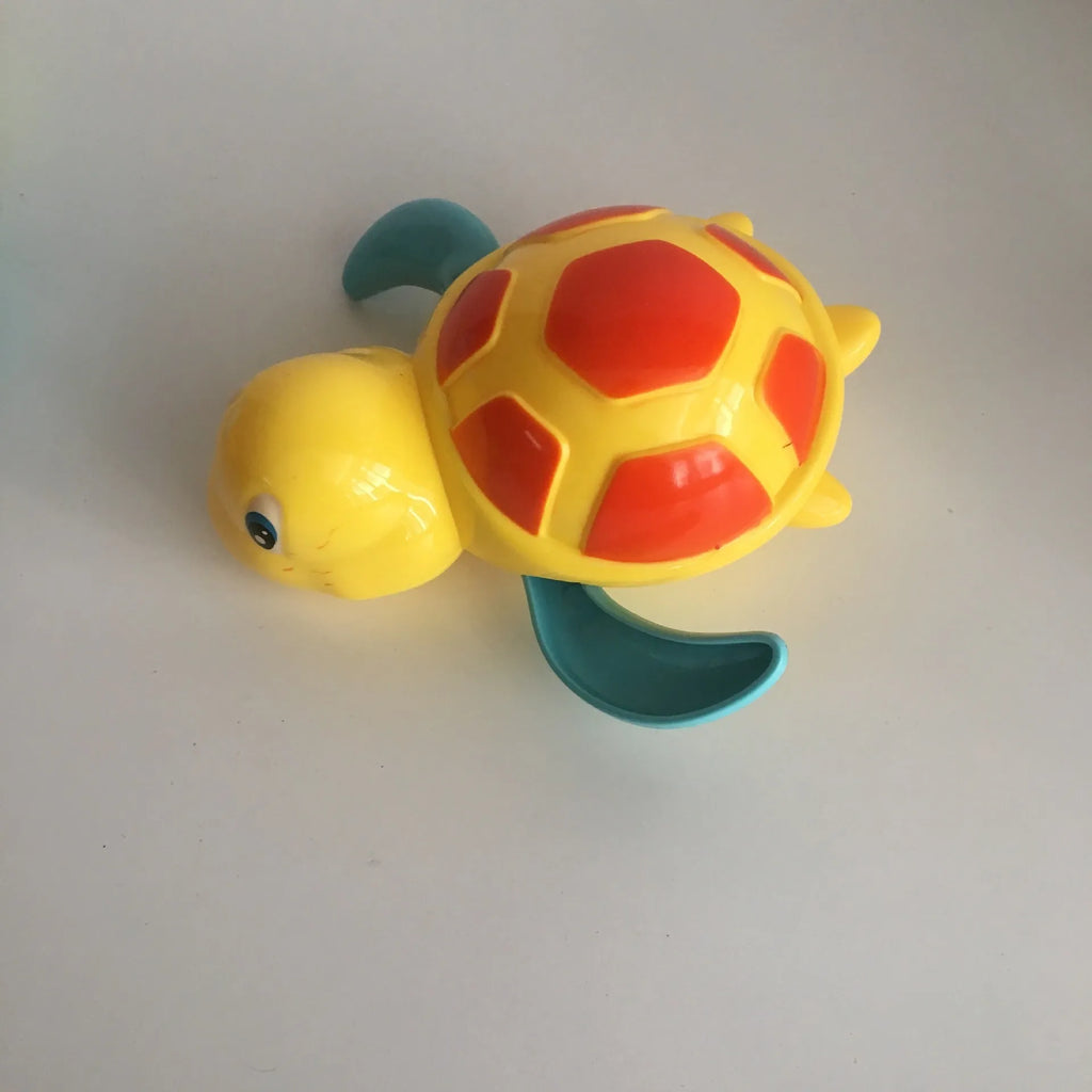 Yellow wind-up plastic turtle water toy on blue surface, 12cm clockwork mechanism