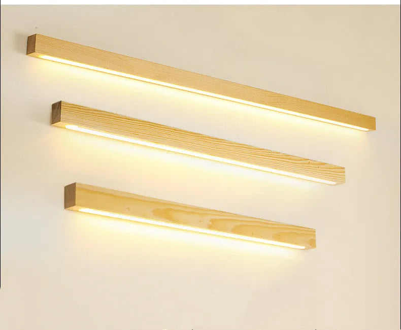 A long, slim walnut-coloured wooden and acrylic LED strip light mounted on a wall.