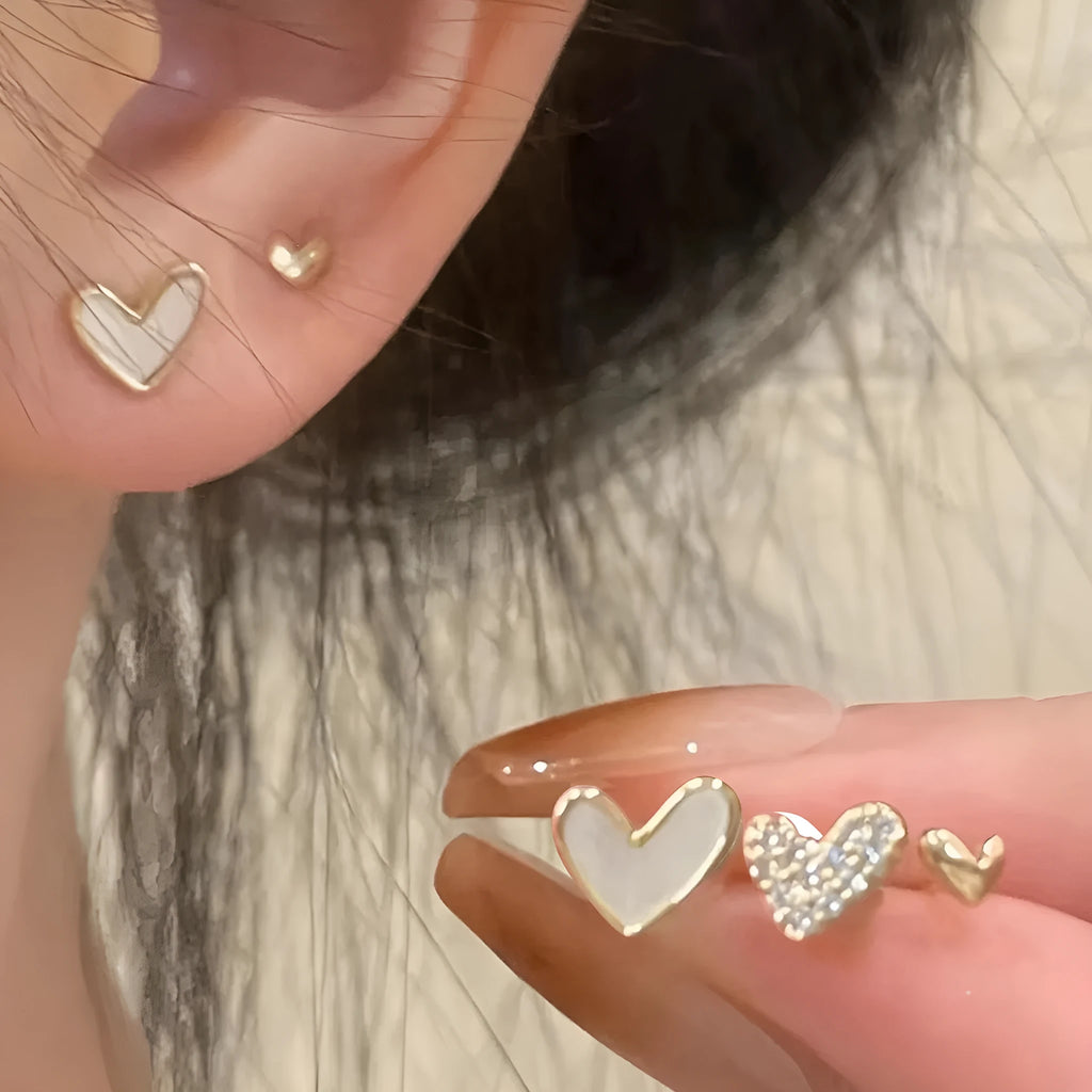 Three pairs of heart-shaped alloy earrings with electroplated finish in gold, black, black-white, and pink colours