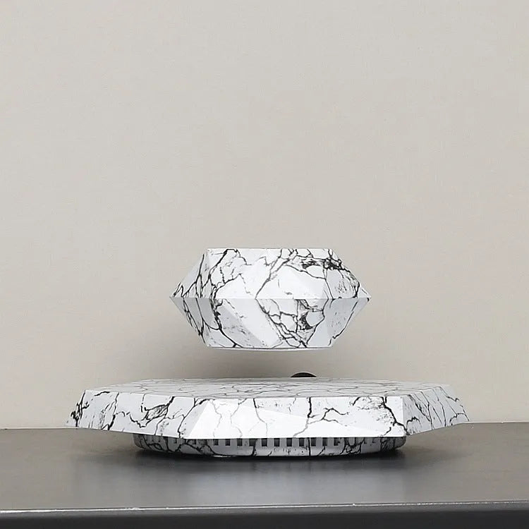 Small marble-colour magnetic levitation plant pot floating and rotating above its floor-standing base.