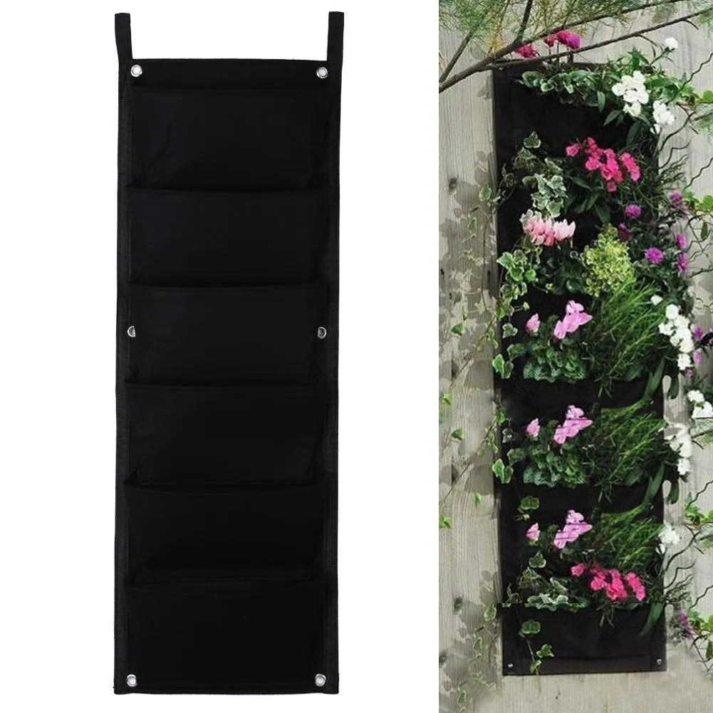 Vertical felt wall garden planting bag with multiple green pockets, hanging on an outdoor fence.