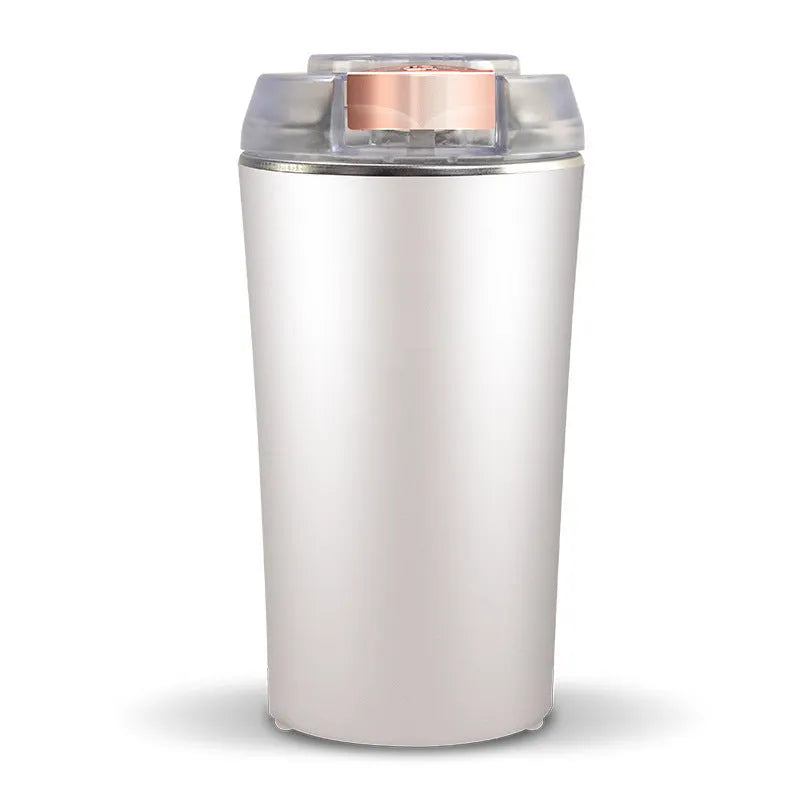 Blue mini flour mill and grain crusher with stainless steel grinding chamber on a countertop.