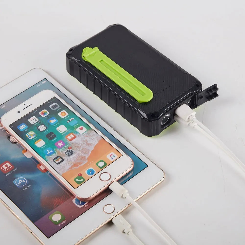 Green or orange hand crank solar power bank with LED light showing USB ports and solar panel.