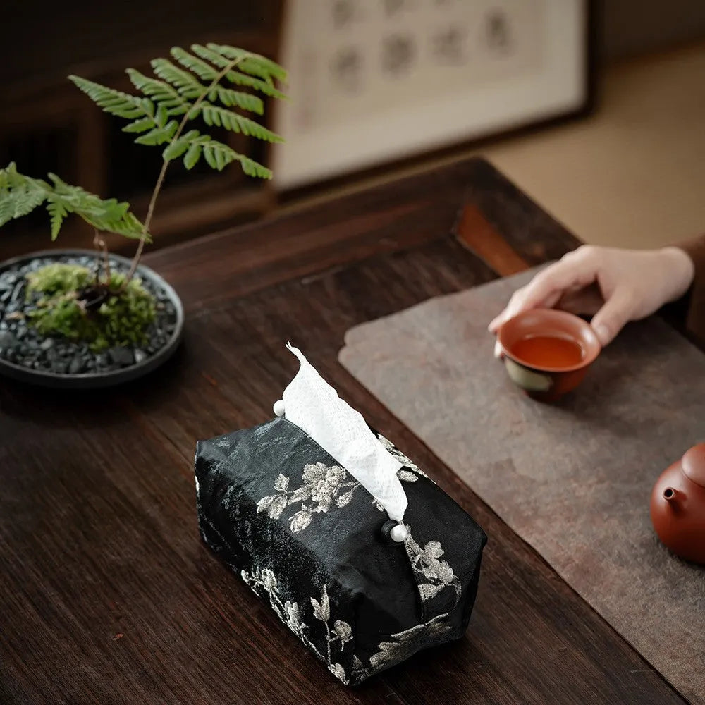 White Chinese brocade tissue box with embroidered plum blossoms, shown with and without a pearl buckle.