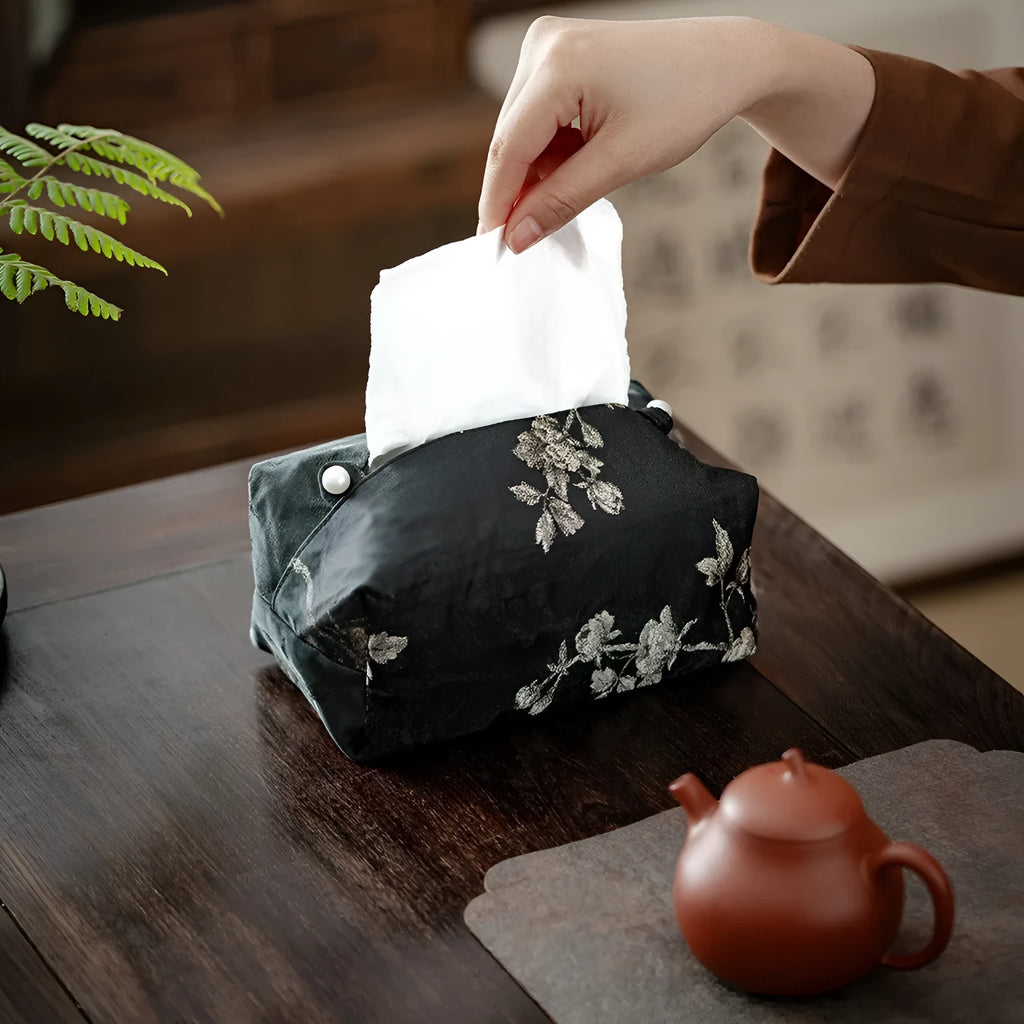 White Chinese brocade tissue box with embroidered plum blossoms, shown with and without a pearl buckle.