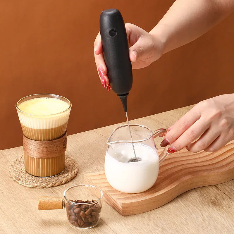 Black and white hand-held electric milk frother blender for coffee preparation