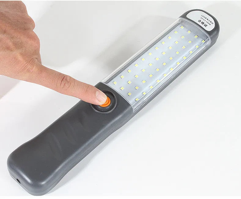 Grey multifunctional LED work light with magnetic base and 360° rotation on a metal surface