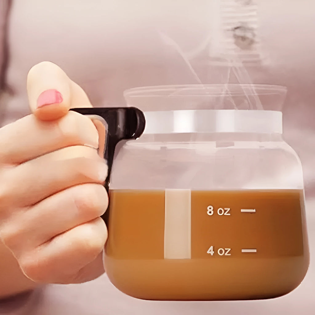 Transparent borosilicate glass coffee maker with a black silicone cover on a wooden table.