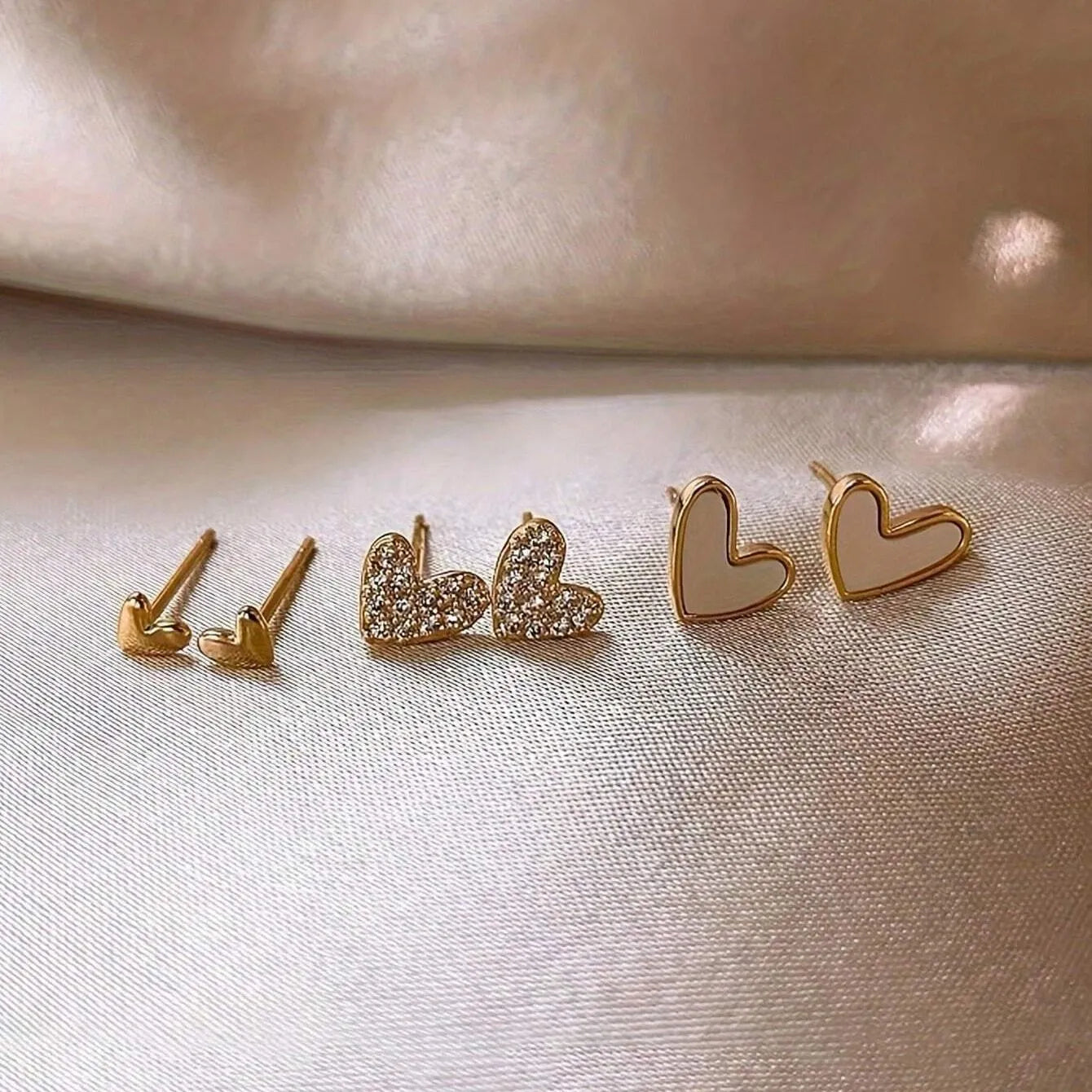 Three pairs of heart-shaped alloy earrings with electroplated finish in gold, black, black-white, and pink colours