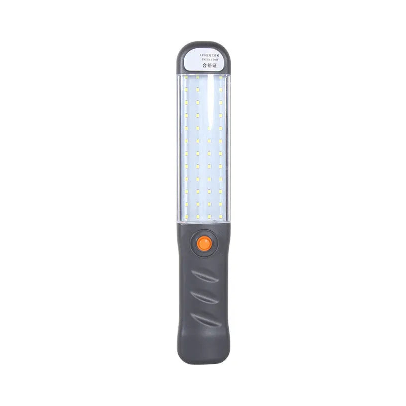 Grey multifunctional LED work light with magnetic base and 360° rotation on a metal surface
