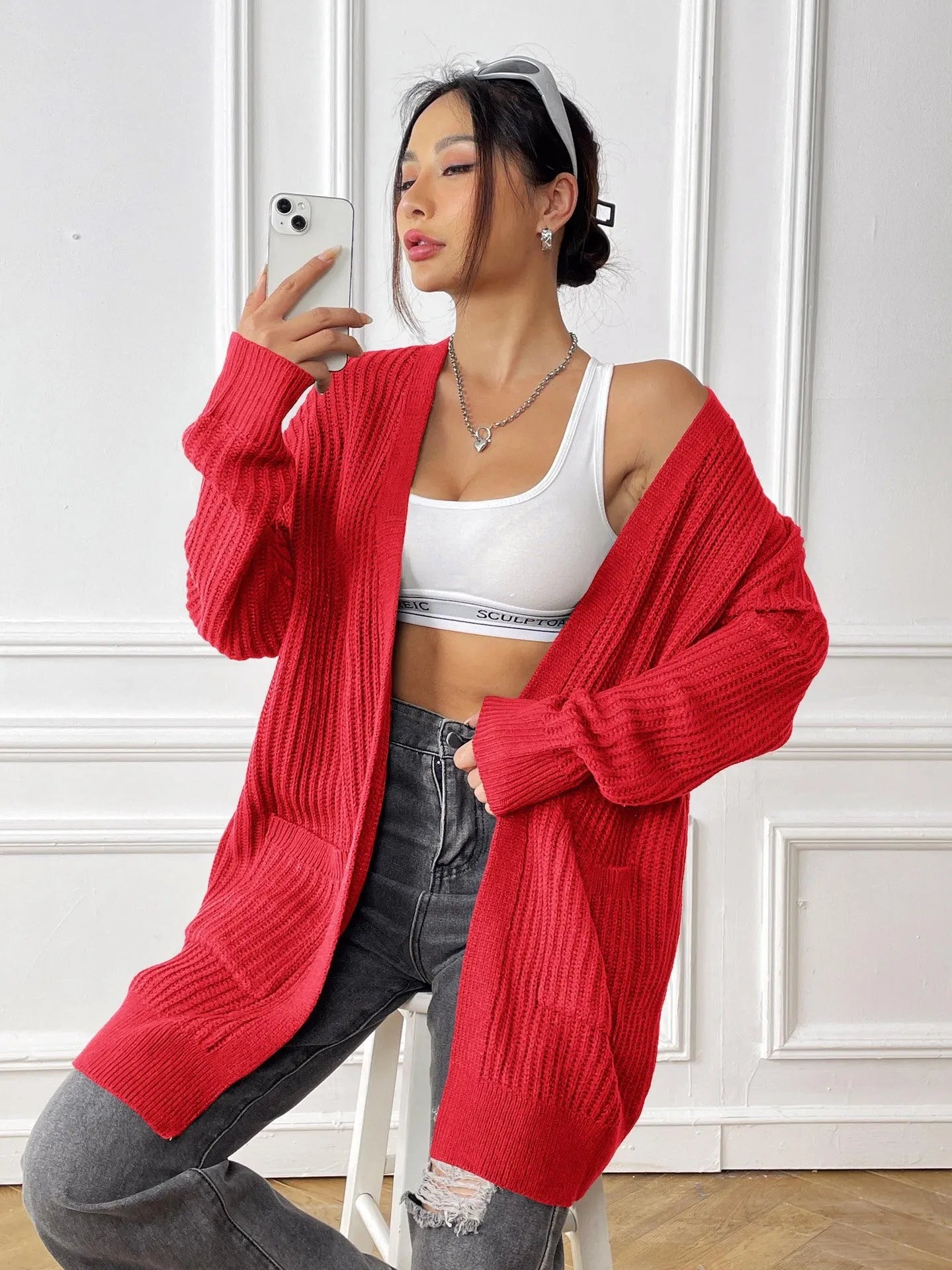 Women's dark green loose-fit cardigan sweater with two front pockets and long sleeves.