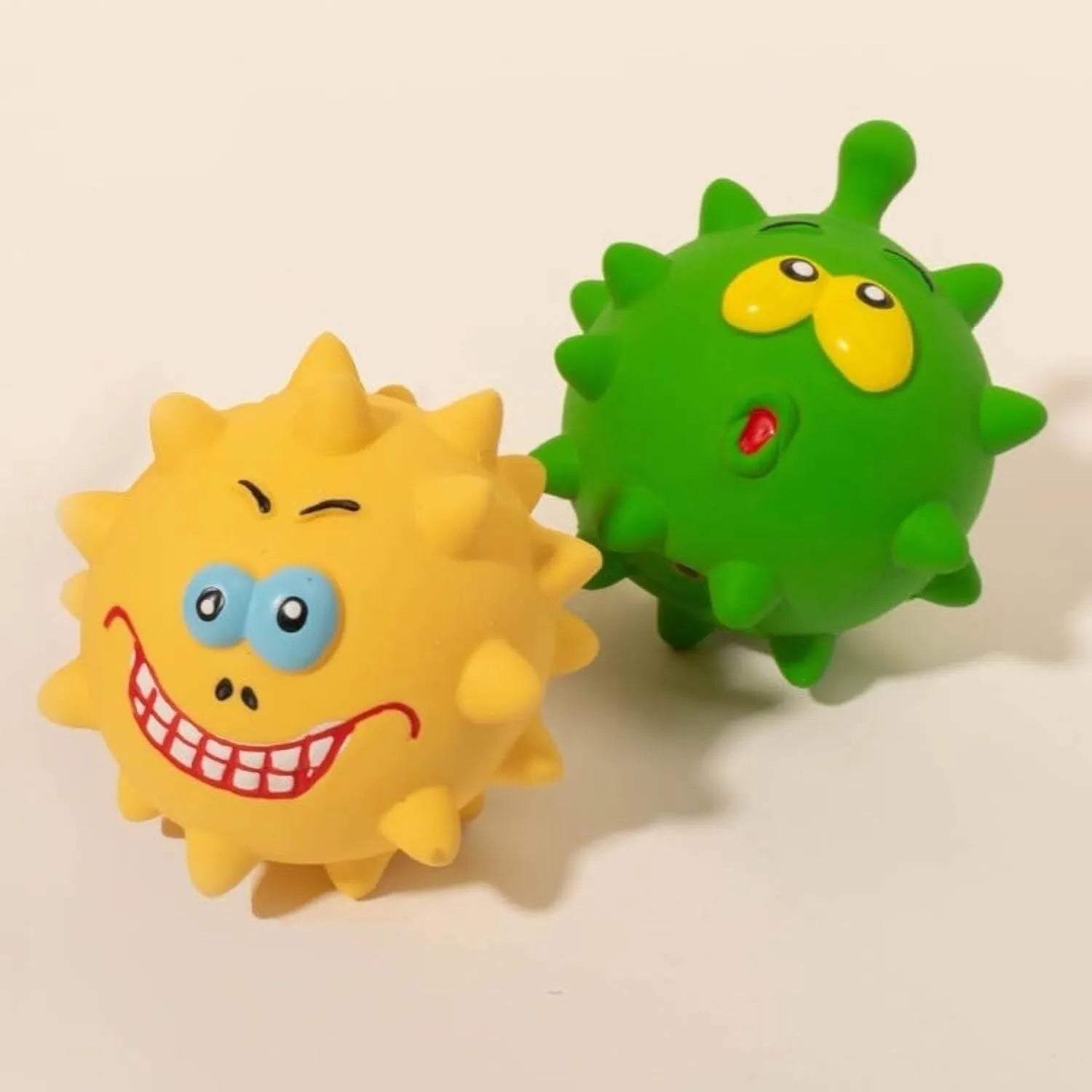 Four colourful squeaky dog balls with cute faces on textured natural latex rubber surfaces