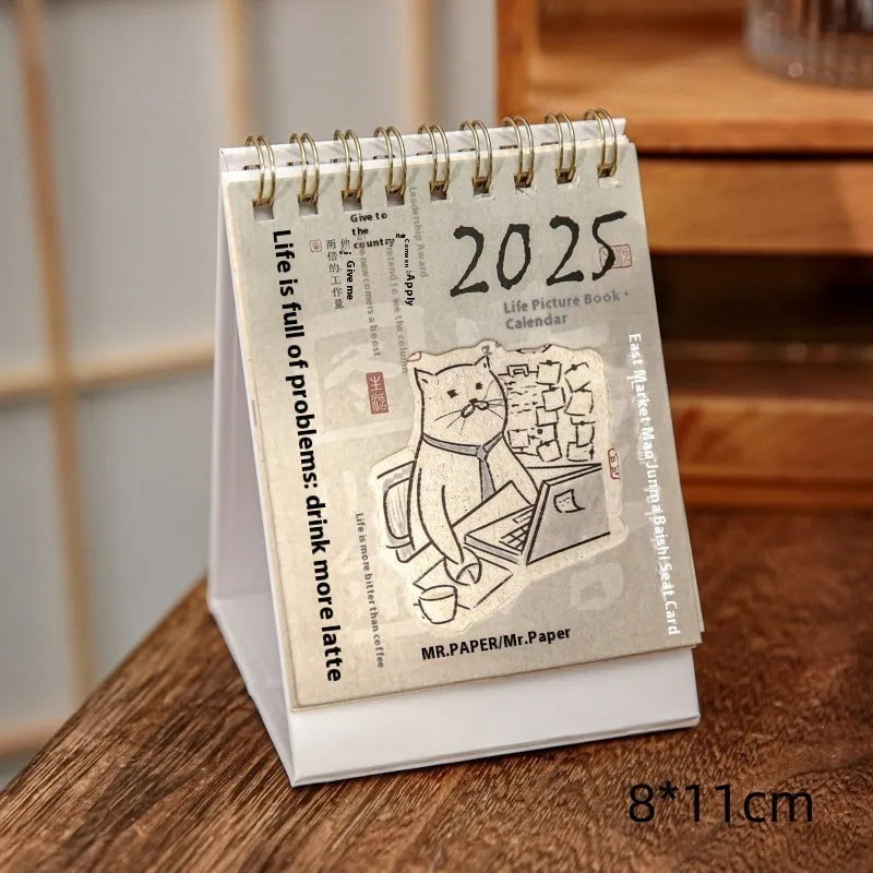 Set of four different 2025 mini paper desk calendars with simple modern designs on a desk.
