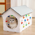 Plastic integrated cat scratch board with attached nest bed and tunnel containing a bell ball toy.