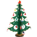 Hand-painted wooden Christmas tree decoration in red and green colours on desktop