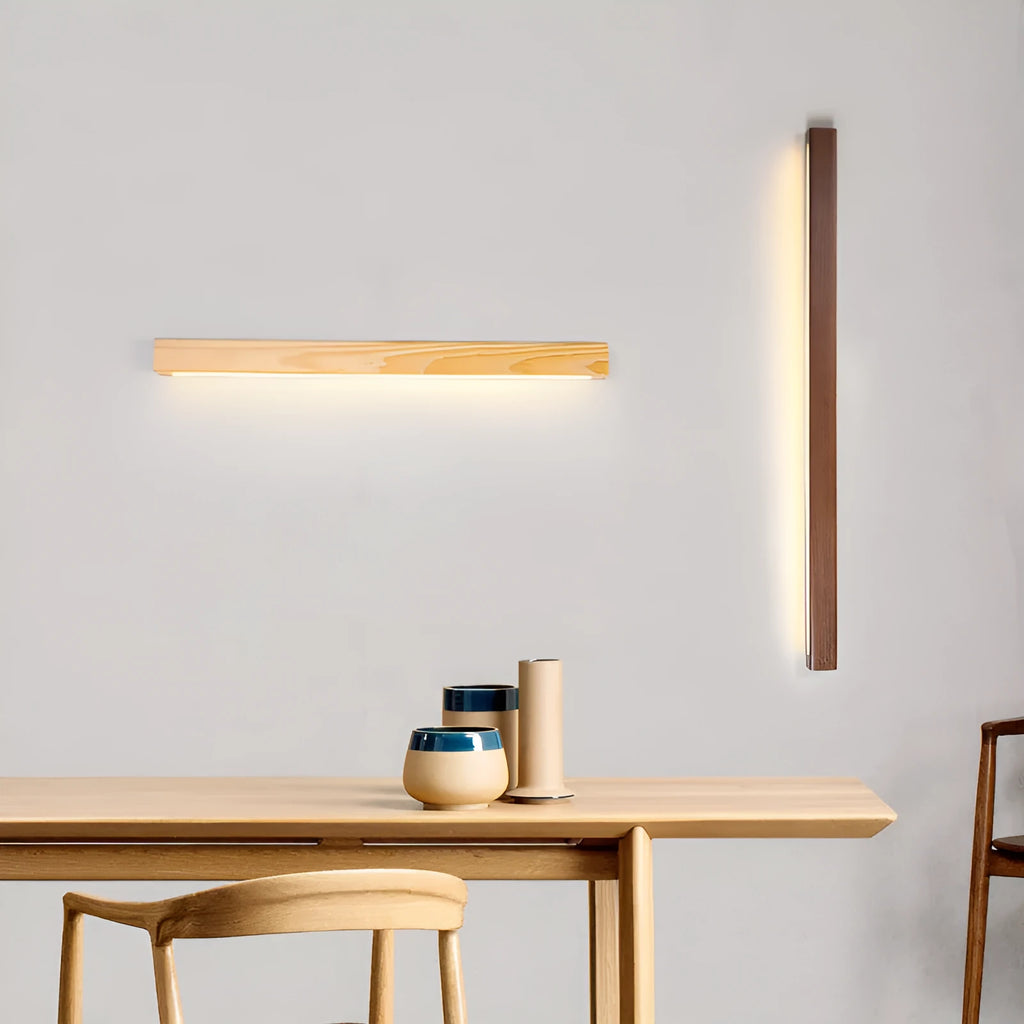 A long, slim walnut-coloured wooden and acrylic LED strip light mounted on a wall.